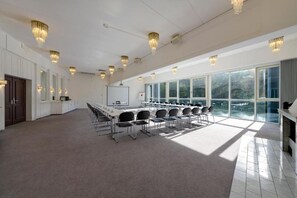 Ein Konferenzraum mit einem langen Tisch, Stühlen, Kronleuchtern und großen Fenstern.