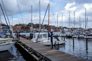 Un port de plaisance avec de nombreux bateaux amarrés, des quais en bois et des bâtiments en arrière-plan.