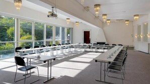 Ein Konferenzraum mit langen Tischen, Stühlen und Kristallleuchtern.