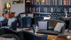 Eine Bibliothek mit Ledersesseln, Bücherregalen und einem alten Grammophon.