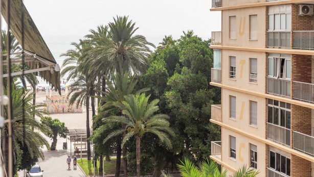 A multi-story building with balconies, a sandy beach in the background, and palm trees. - Apartment 'Playa A Los Pies Del Castillo' with Sea View, Wi-Fi and Air Conditioning (Cullera)