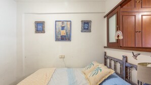 A bedroom with a bed, a nightstand, a mirror, and a door with a wooden frame. - Apartment 'Playa A Los Pies Del Castillo' with Sea View, Wi-Fi and Air Conditioning (Cullera)