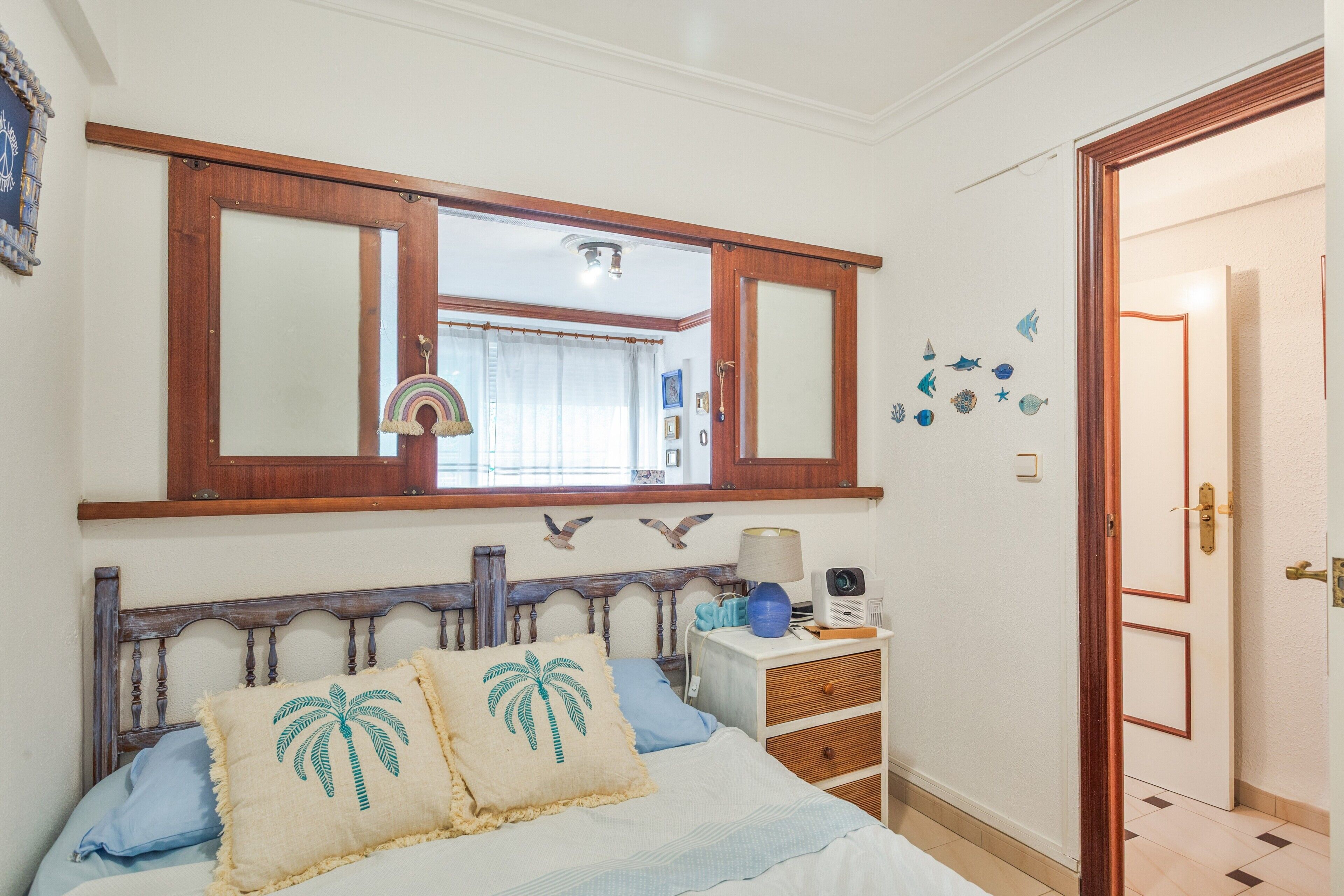 Ein Schlafzimmer mit Bett, Nachttisch, Spiegel und einer Tür.