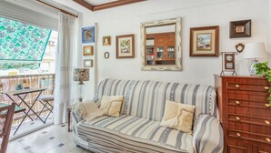 A room with a striped sofa, a wooden dresser, and a mirror on the wall.