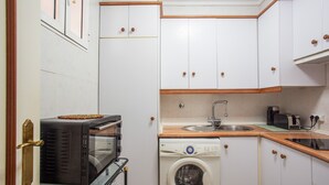 A compact kitchen with a washing machine, a toaster, and a sink.