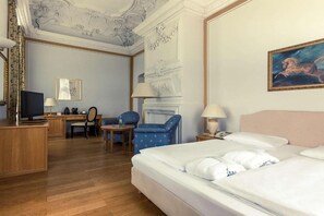 A hotel room with a bed, desk, chair, television, and a fireplace.