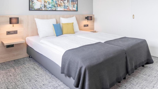 A double bed with two bedside tables, a headboard, and a wall-mounted artwork. - Sunday Hotel Flensburg Double room (Flensburg)