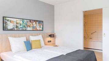 Una habitación de hotel con cama, un cuadro, una mesita de noche y un baño con ducha.