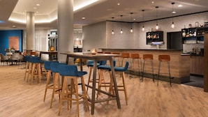 A modern bar area with wooden stools, a bar counter, and hanging pendant lights. - Sunday Hotel Flensburg Double room (Flensburg)