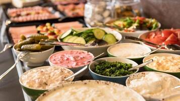 A buffet with various dishes including salads, dips, and a variety of meats.