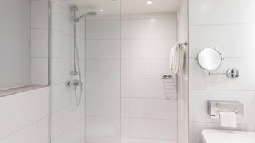 Ein modernes Badezimmer mit einer Duschkabine aus Glas, einem weißen Waschbecken, einem Spiegel und einem Handtuchhalter.