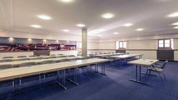 A conference room with multiple tables and chairs, a large pillar, and a cityscape mural on the wall.