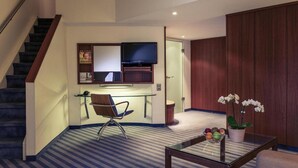 Ein Hotelzimmer mit Schreibtisch, Stuhl, Fernseher und großem Kleiderschrank.