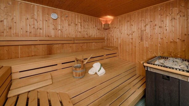 Eine Holzsauna mit Bänken, einem Holzeimer und Handtüchern.