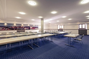 A conference room with multiple tables and chairs, a large pillar, and a cityscape mural on the wall.