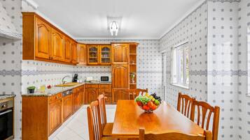 A kitchen with wooden cabinets, a dining table, and chairs.