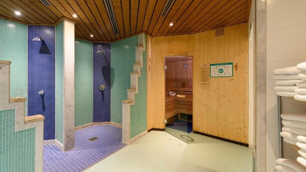 Una sala de sauna con techo de madera, paredes de azulejos y un banco.