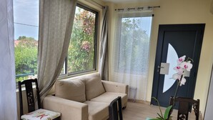 A room with a sofa, a small table, a chair, a potted plant, and a door with a large window. - 3-bedroom house in serene Carry-le-Rouet with cool AC (Carry-le-Rouet)