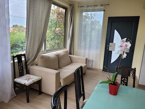 A room with a sofa, a small table, a chair, a potted plant, and a door with a large window. - 3-bedroom house in serene Carry-le-Rouet with cool AC (Carry-le-Rouet)