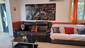 A living room with a black leather sofa, a white sofa with patterned cushions, a glass coffee table, and a large wall art piece. - 3-bedroom house in serene Carry-le-Rouet with cool AC (Carry-le-Rouet)
