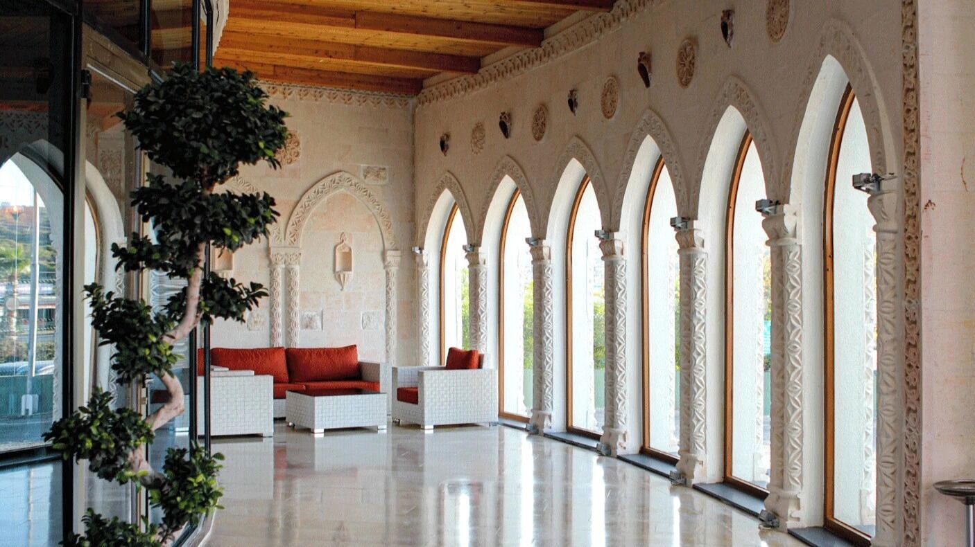 A spacious interior with a high ceiling, arched windows, and a seating area with white furniture.