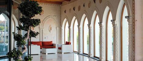 A spacious interior with a high ceiling, arched windows, and a seating area with white furniture.