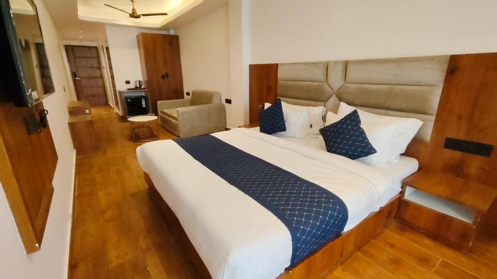 Une chambre d’hôtel avec un grand lit, un petit bureau, une chaise et un téléviseur.