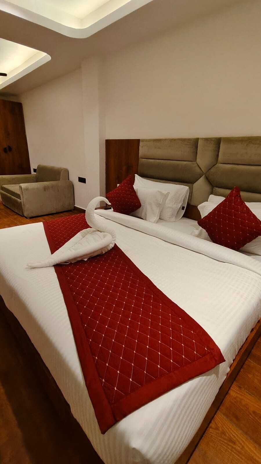 Ein Hotelzimmer mit einem großen Bett, einem Holzkopfende und einem roten Zierkissen.