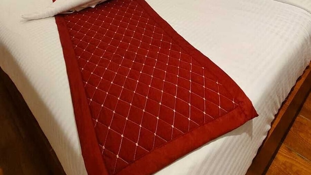 A hotel room with two beds, a sofa, and a wooden floor. - Hotel Varanasi Ganges (Varanasi)