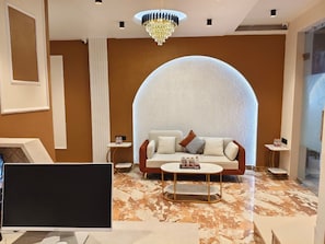 Una sala moderna con sofá, mesa de centro y un amplio arco en la pared.