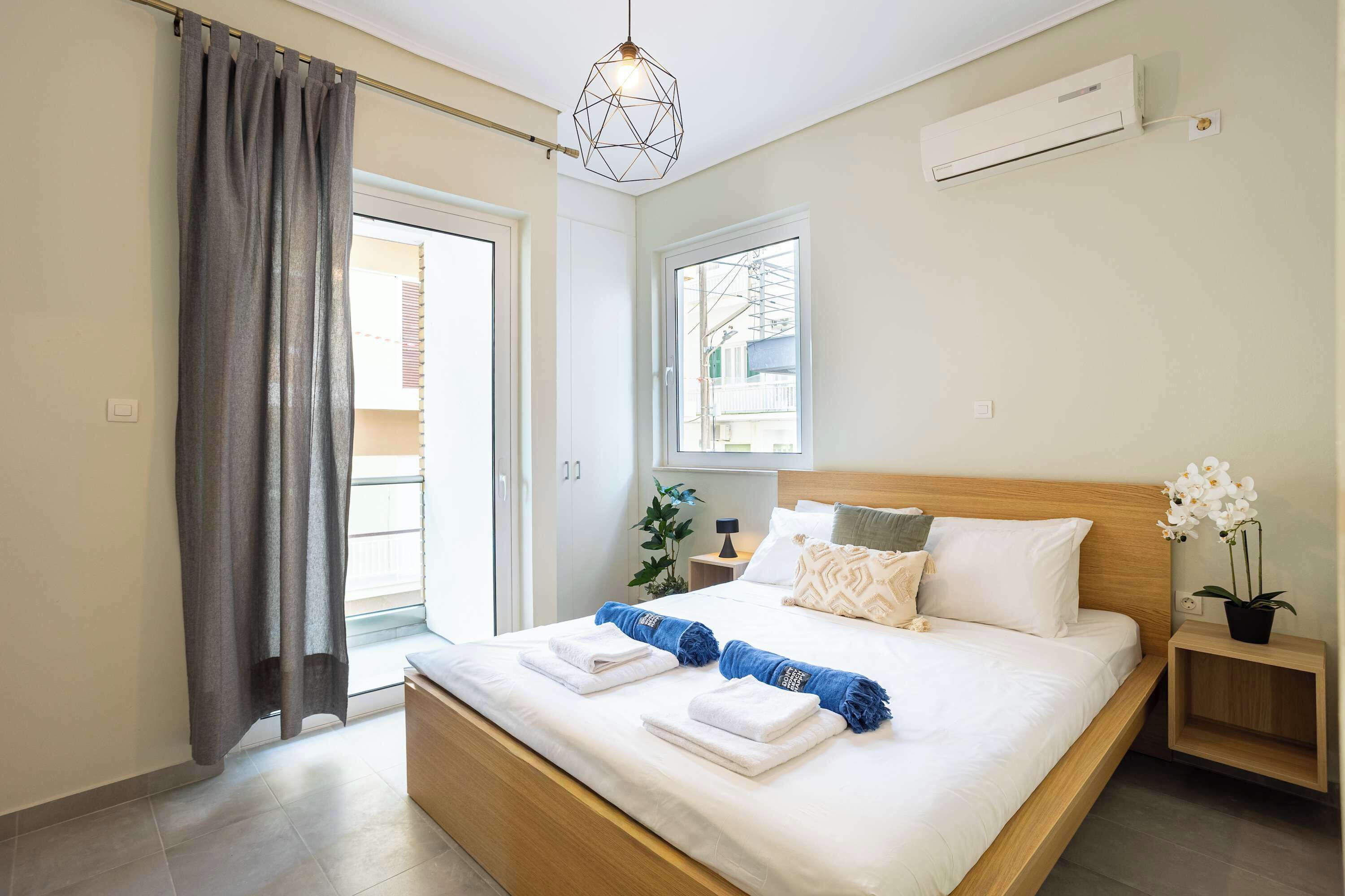 Ein Schlafzimmer mit Bett, Nachttisch, Topfpflanze, Fenster und Klimaanlage.