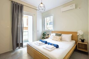 Une chambre à coucher avec un lit, une table de chevet, une plante en pot, une fenêtre et un appareil de climatisation.