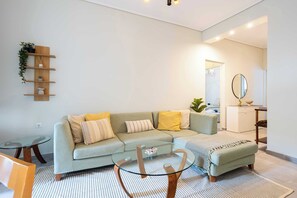 A modern living room with a sectional sofa, a glass coffee table, and a small side table. - Seaside Retreat for Relaxed Kalamata Beach Stays (Kalamata)