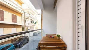 Ein Balkon mit Holztisch, einem Stuhl, einer Topfpflanze und einer Fruchtschale.