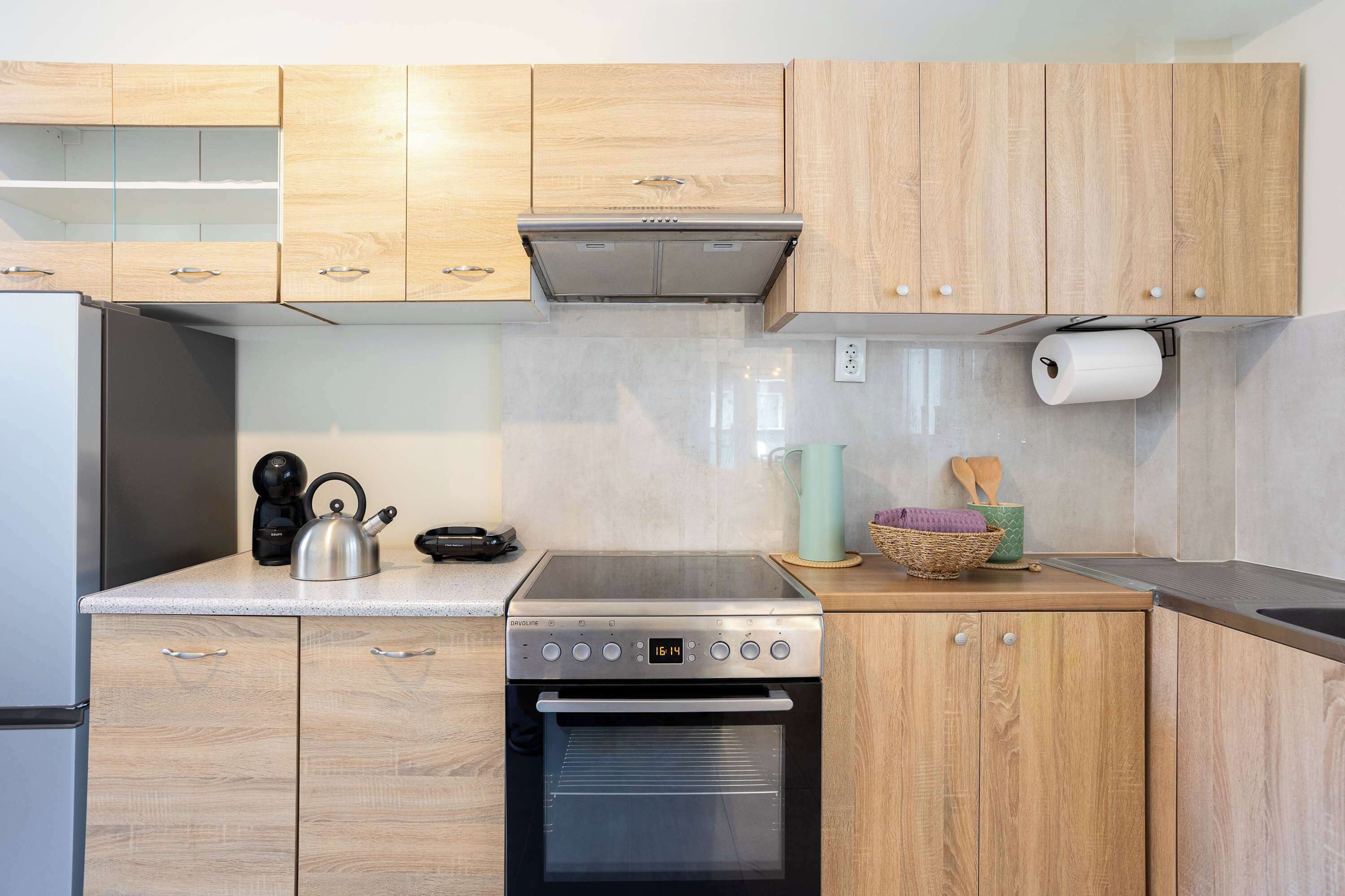 Una cucina con mobili in legno, una cappa aspirante in acciaio inossidabile, un forno integrato e una macchina per il caffè.