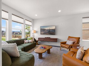 A spacious living room with a green sofa, a brown leather chair, and a wooden coffee table. - New! Deer Valley Close, 4BR 3.5BA, Sleeps 11, BBQ (Heber City)