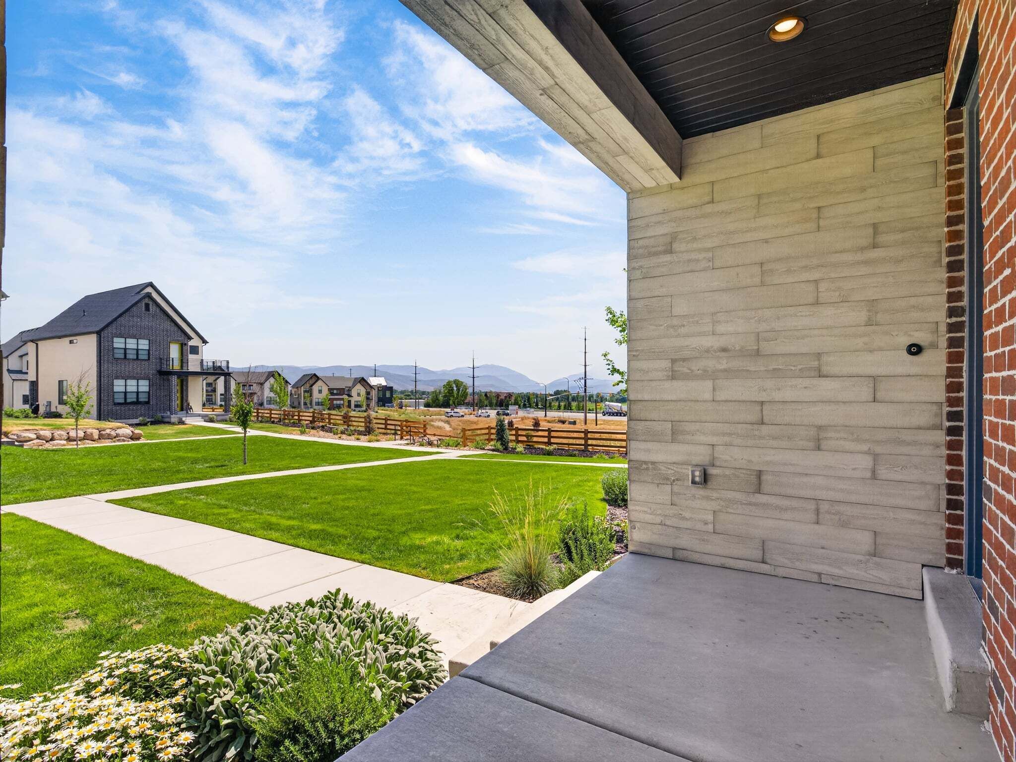 A residential area with a modern house featuring a brick exterior and a covered porch.