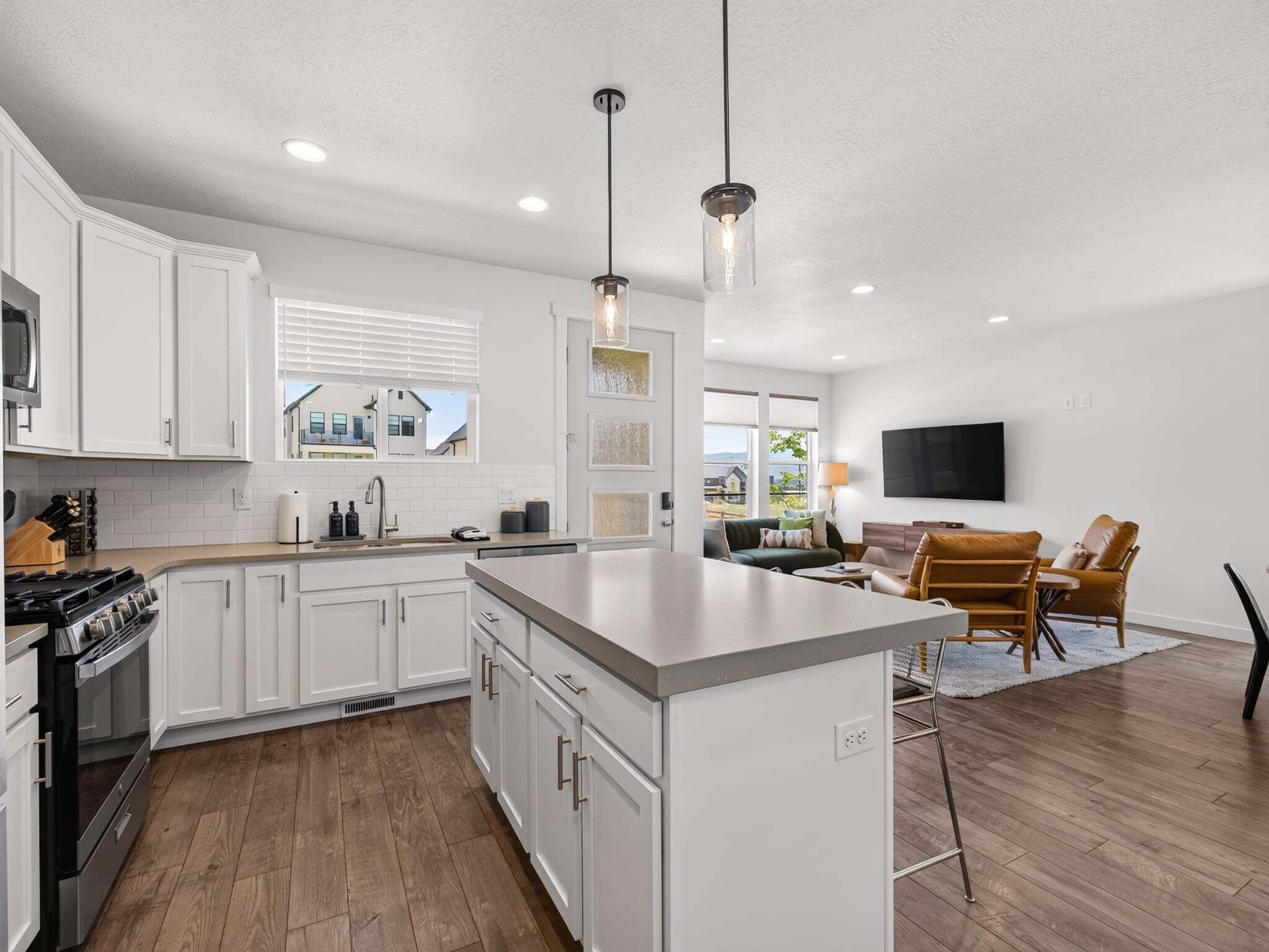 A modern kitchen with white cabinetry, a central island, and a dining area with a TV.