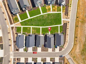 An aerial view of a residential area with a central green space, a red location marker, and a road with vehicles. - New! Deer Valley Close, 4BR 3.5BA, Sleeps 11, BBQ (Heber City)