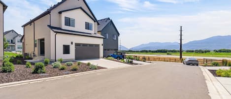 A two-story residential house with a garage, driveway, and landscaped garden.