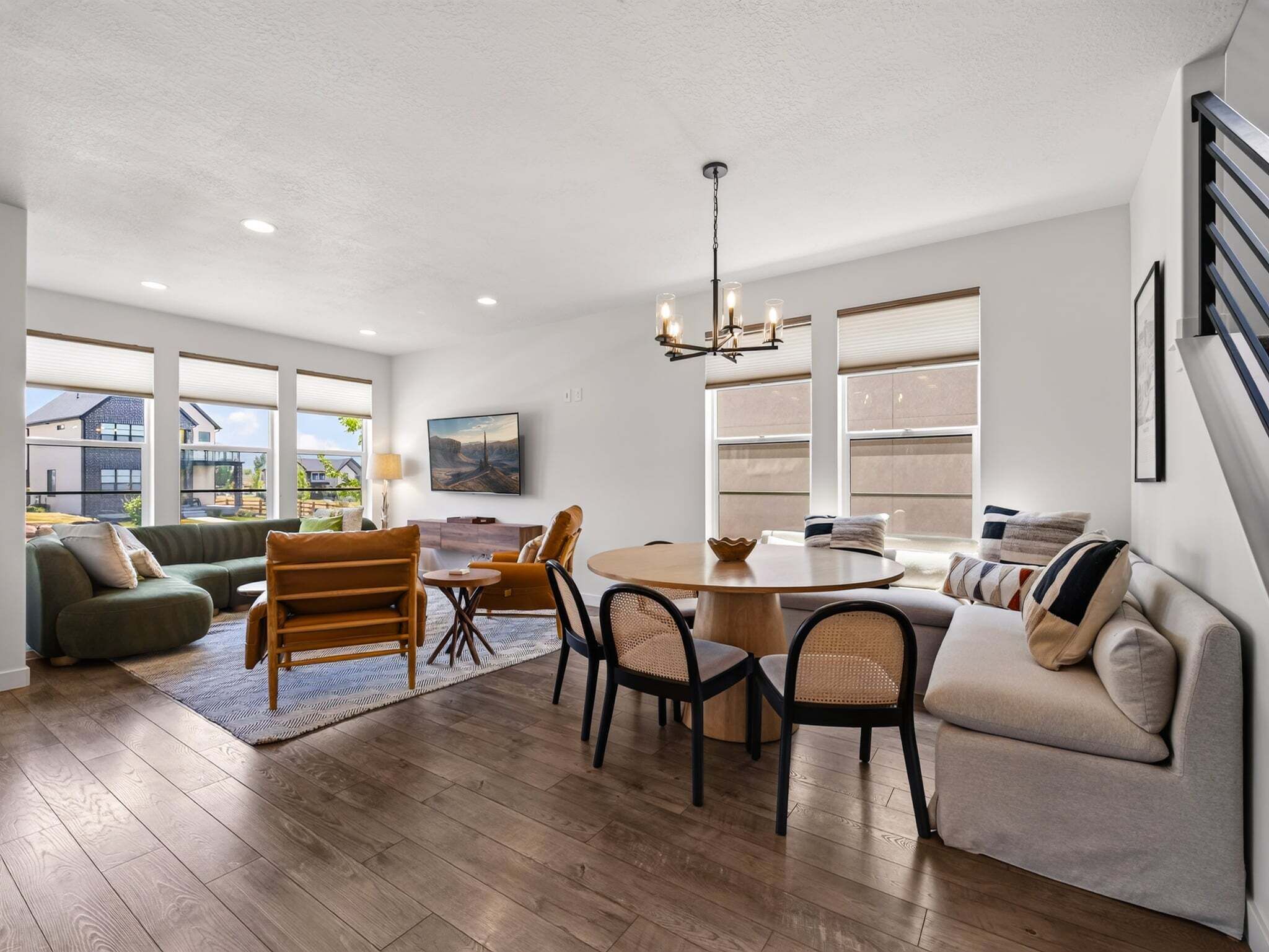A spacious living area with a dining table, sofas, and a chandelier.