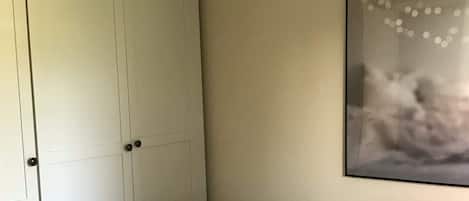A bedroom with a bed, a wardrobe, and a wall-mounted artwork.