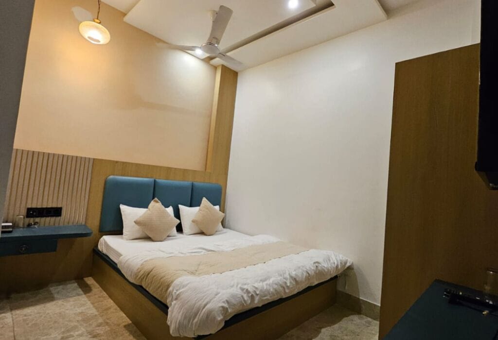 A bedroom with a bed, bedside tables, a ceiling fan, and a wall-mounted light fixture.