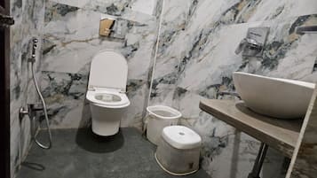 A bathroom with a toilet, bidet, and sink against marble walls.