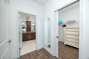 A hallway leading to a bathroom with a mirror, a dresser, and a shelf with items. - Home Near Belleair Beach (Largo)