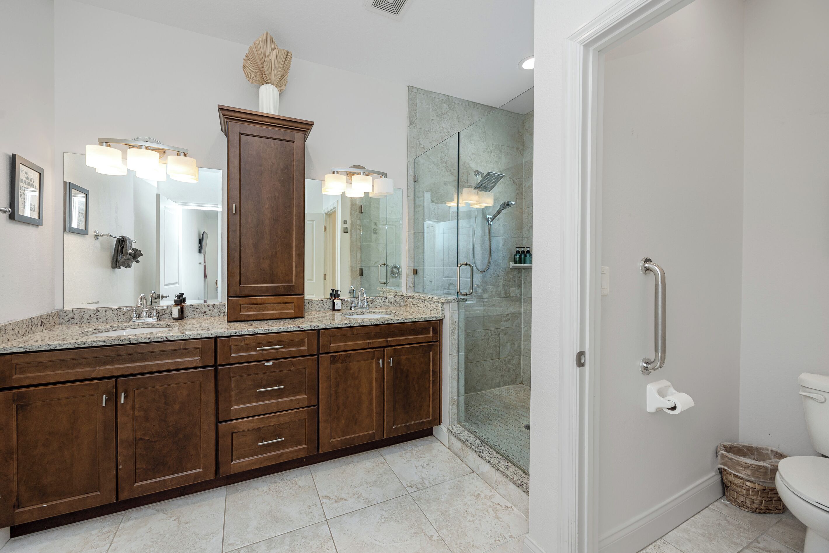A bathroom with a large wooden vanity, a glass shower enclosure, and a white toilet.