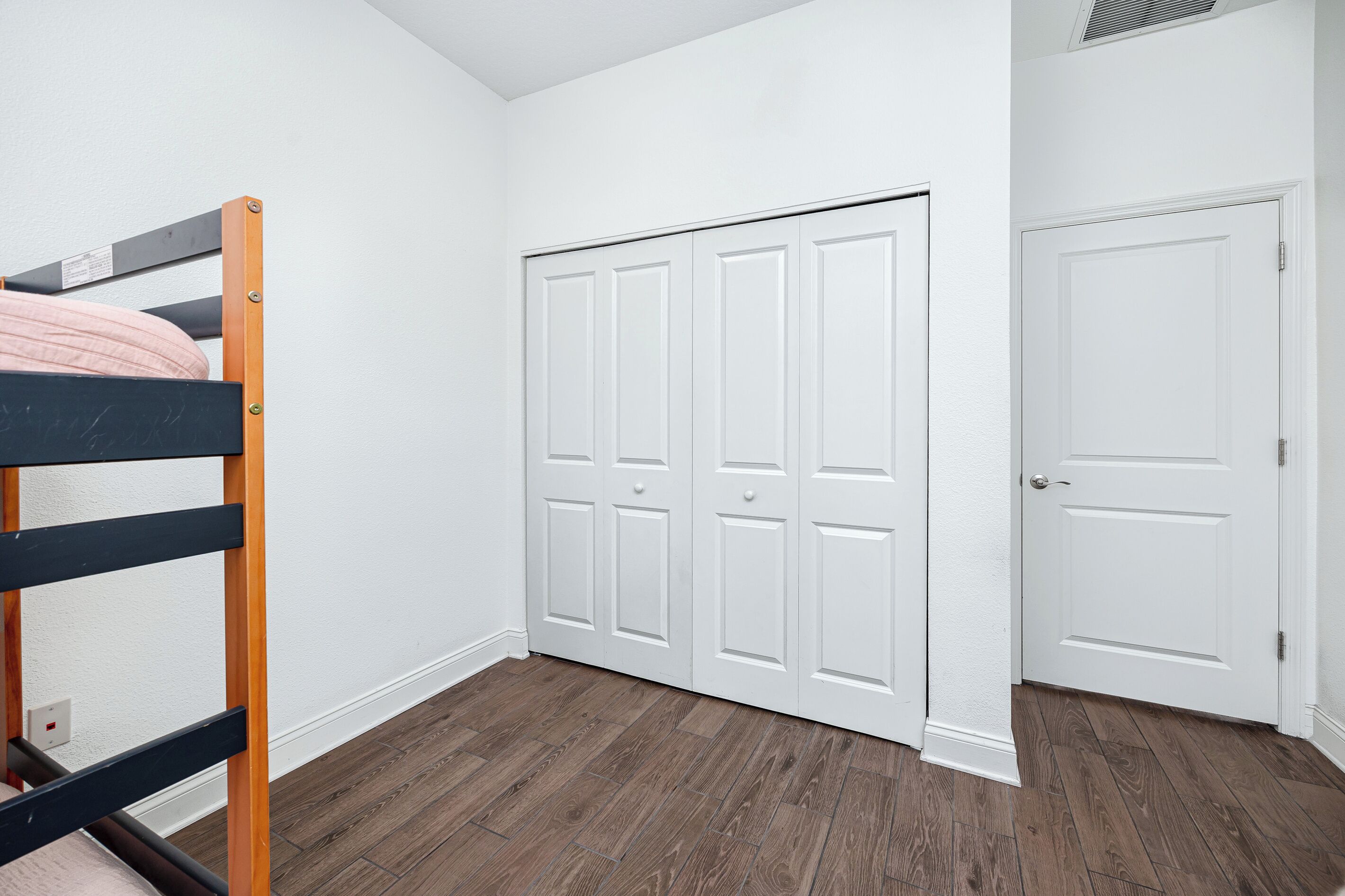 A room with a bunk bed, a white wardrobe, and a closed door.