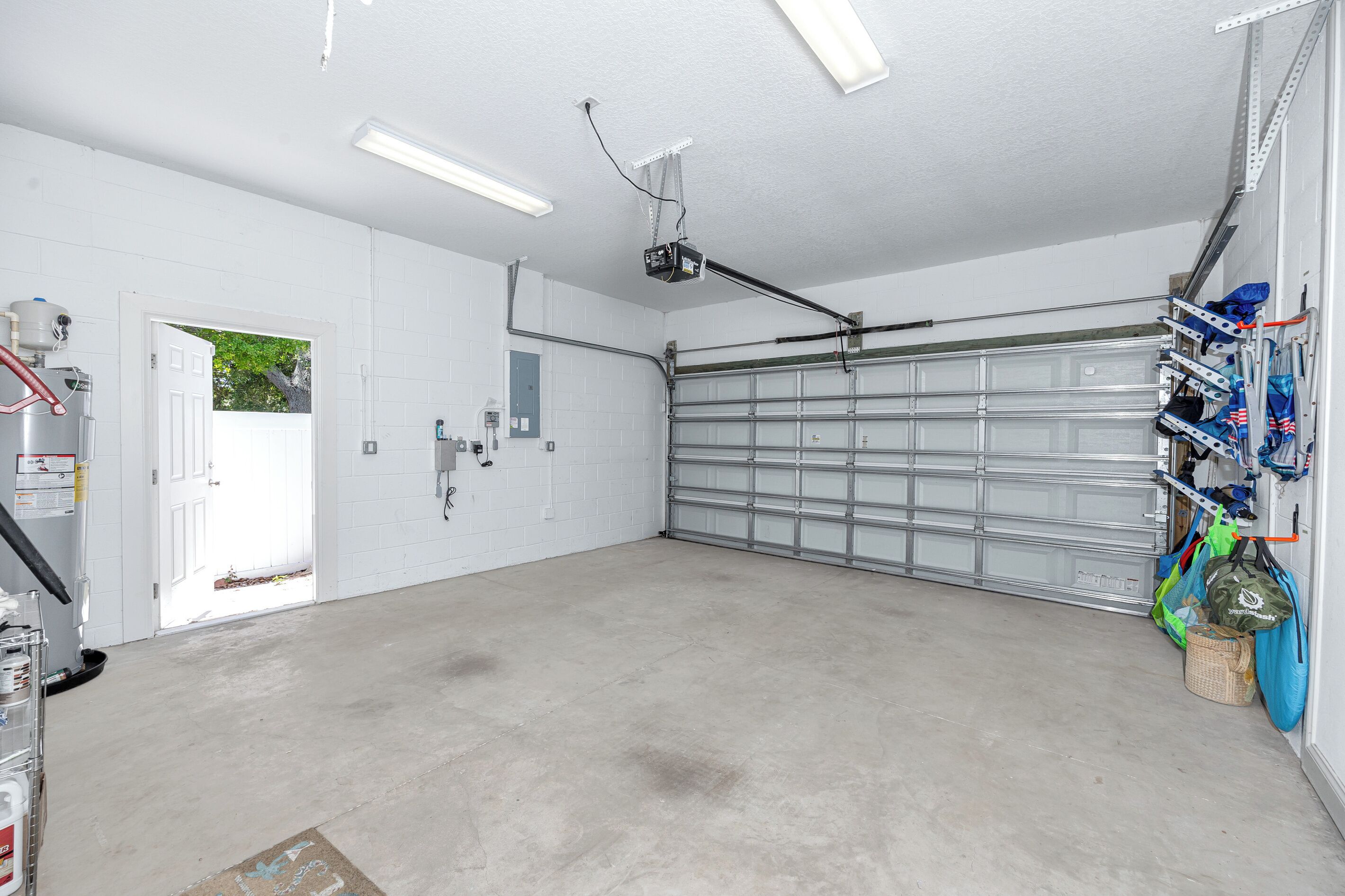 Een garage met een witte deur, een projector in het plafond en een gereedschapskast aan de muur.