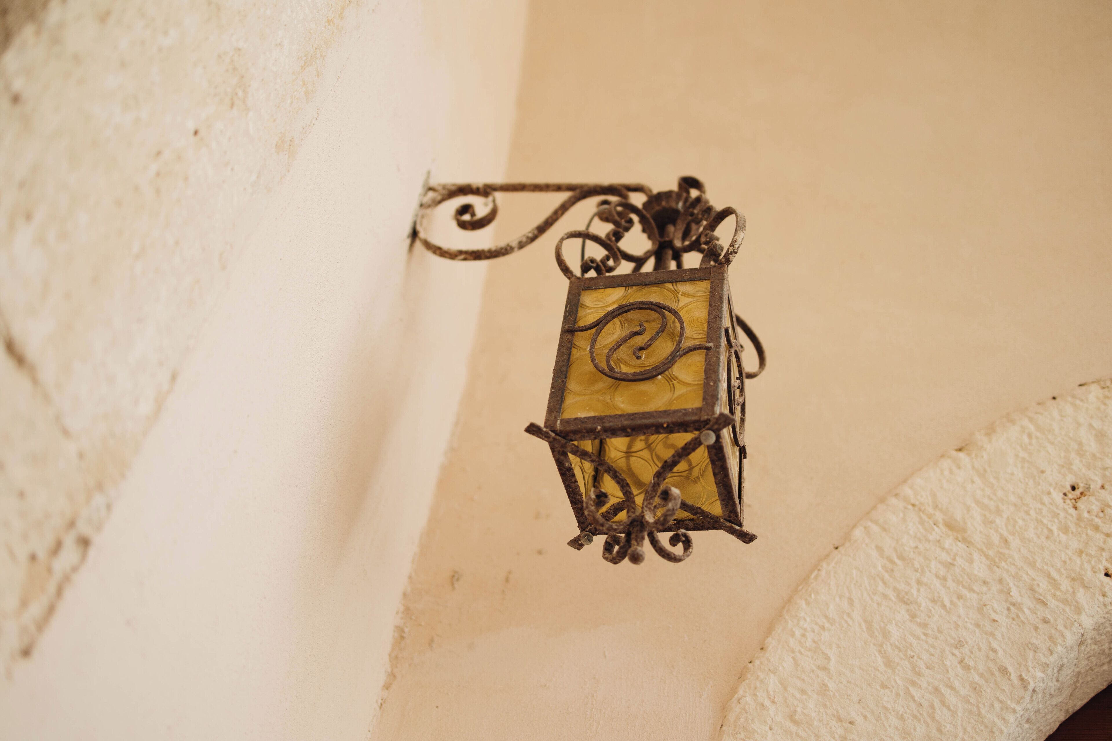 Una linterna fijada a la pared, con estructura metálica decorativa y panel de vidrio.