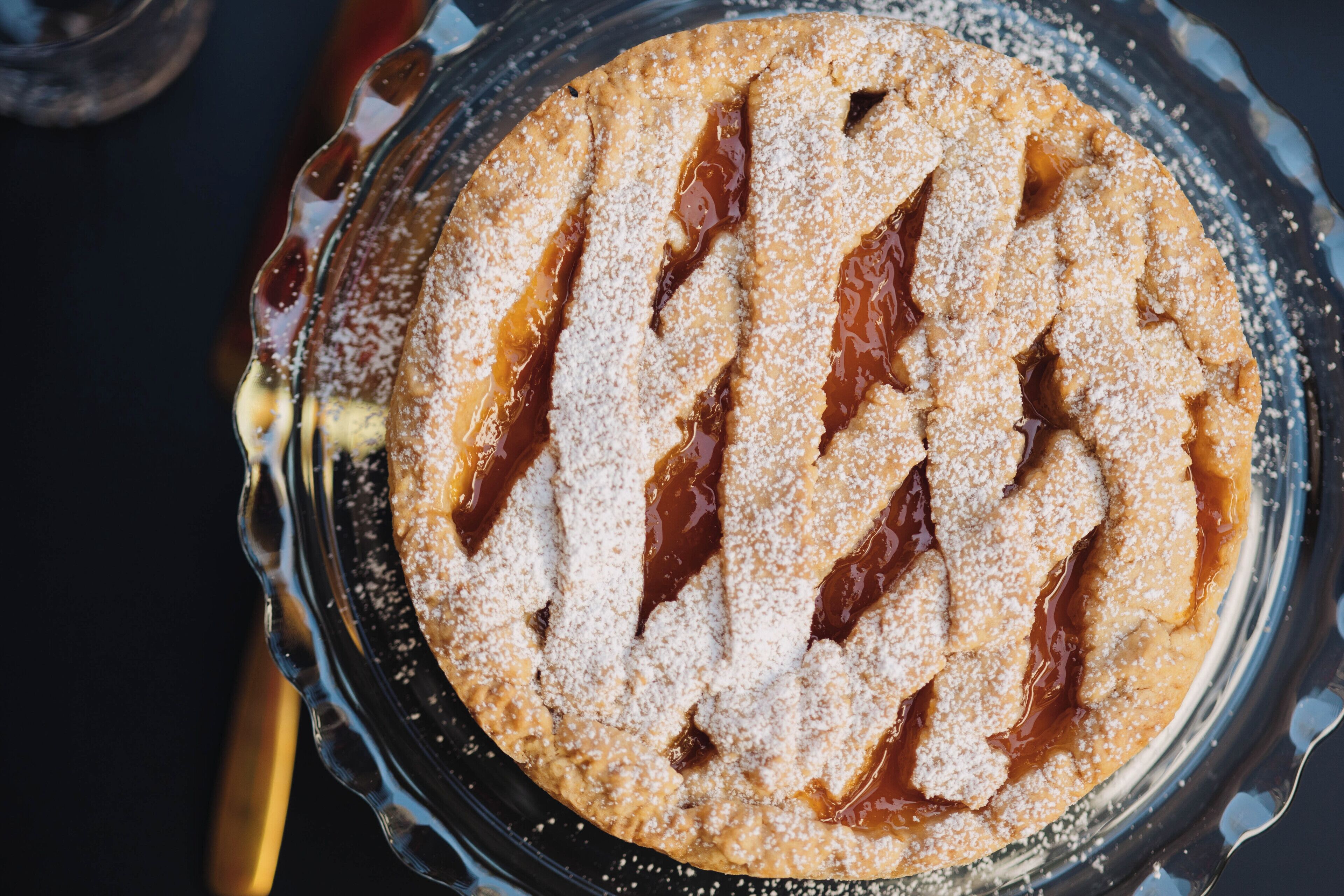 A round dessert with a crisscross pattern on top, dusted with powdered sugar.